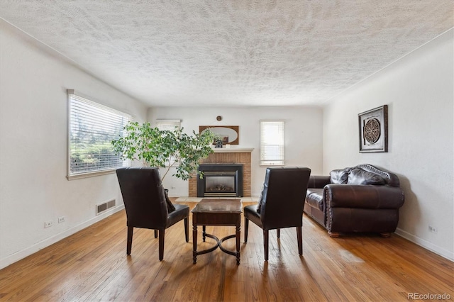 3201 S Albion St, Denver, CO 80222 - living area featuring hardwood / wood-style floors, healthy amount of natural light, baseboards, a brick fireplace, and a textured ceiling