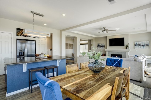 6880 Backcountry Loop, Colorado Springs, CO 80927 - dining space with wood finished floors, ceiling fan, a warm lit fireplace, recessed lighting, and a tray ceiling