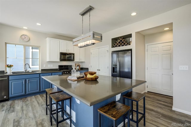 6880 Backcountry Loop, Colorado Springs, CO 80927 - kitchen featuring stainless steel appliances, a sink, blue cabinetry, dark countertops, and wood finished floors