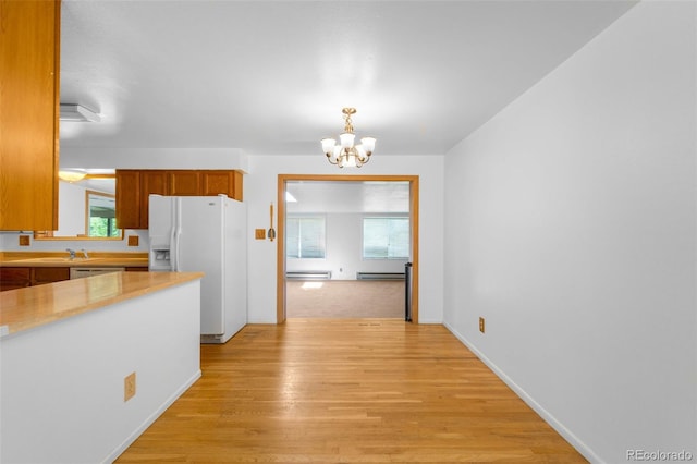 6953 Ingalls St, Arvada, CO 80003 - kitchen featuring white refrigerator with ice dispenser, a chandelier, baseboard heating, light countertops, and light wood-type flooring