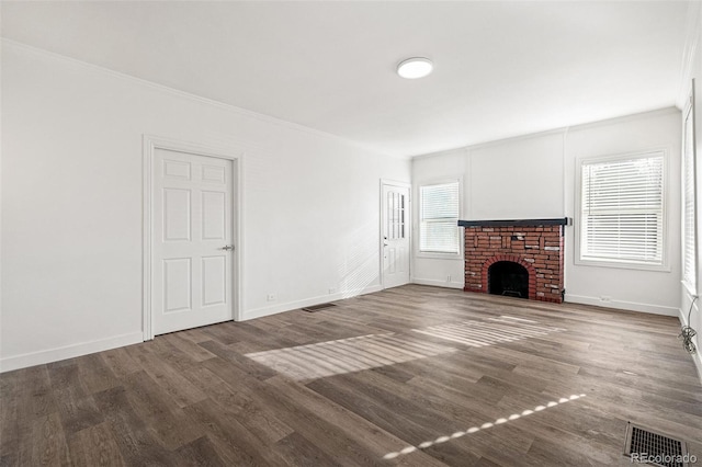 unfurnished living room featuring ornamental molding, hardwood / wood-style flooring, a brick fireplace, and a healthy amount of sunlight