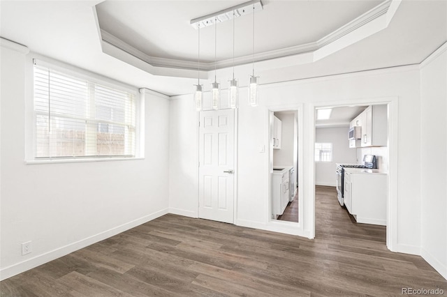 interior space with dark hardwood / wood-style flooring, a tray ceiling, and ornamental molding