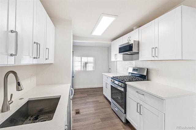 kitchen featuring white cabinets, sink, stainless steel appliances, and light hardwood / wood-style flooring