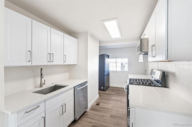 kitchen with white cabinets, appliances with stainless steel finishes, wall chimney exhaust hood, and sink