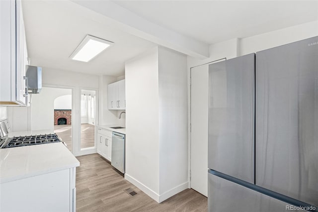 kitchen featuring sink, light wood-type flooring, white cabinetry, and stainless steel appliances