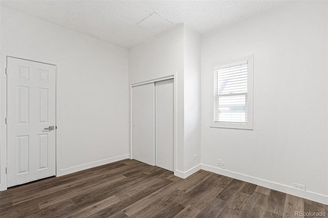 unfurnished bedroom with a textured ceiling and dark hardwood / wood-style flooring