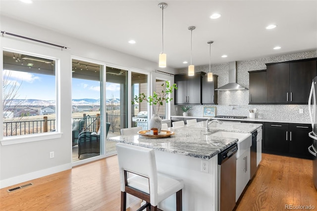 kitchen featuring a center island with sink, visible vents, wall chimney exhaust hood, stainless steel appliances, and a mountain view