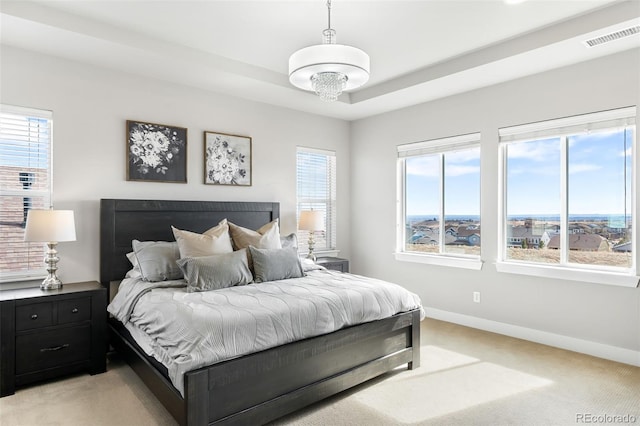 bedroom with a raised ceiling, light colored carpet, visible vents, and baseboards