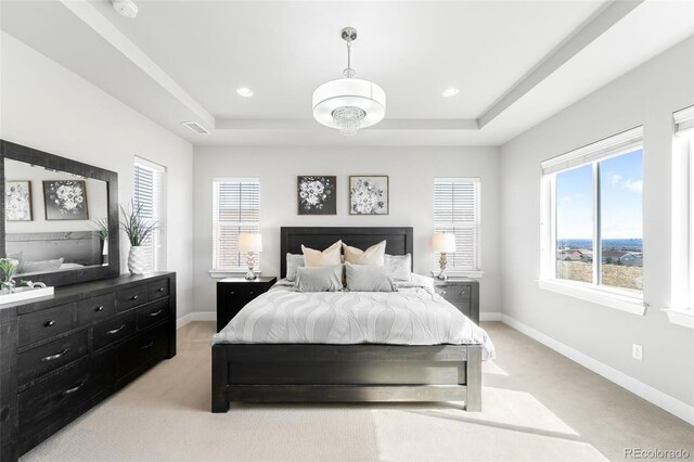 bedroom with a tray ceiling, visible vents, and baseboards