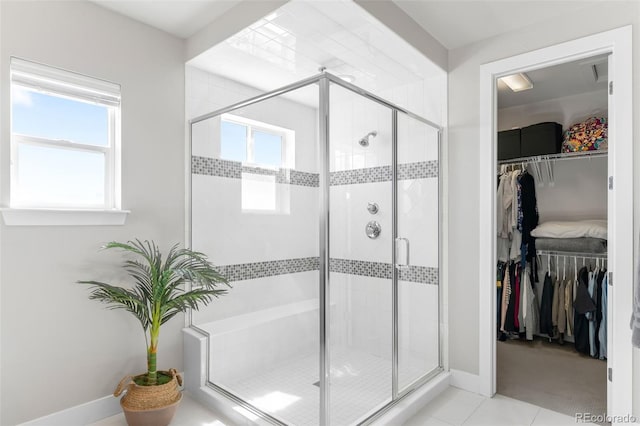 full bath with a shower stall, a spacious closet, baseboards, and tile patterned floors