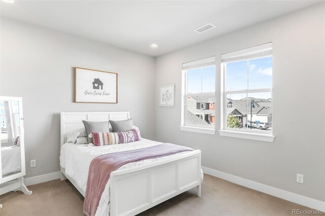 bedroom with baseboards, visible vents, and light colored carpet