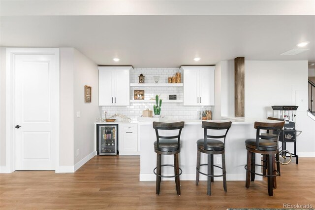 kitchen featuring light countertops, wine cooler, and white cabinets