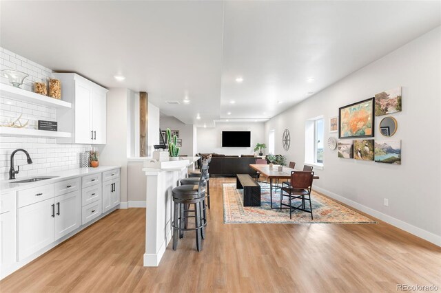 kitchen with light countertops, a breakfast bar, a sink, and white cabinets