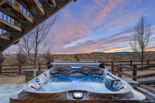 yard at dusk with a hot tub, fence, and a mountain view