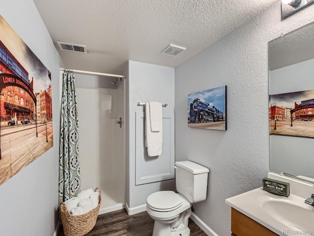 6065 Wadsworth Blvd Unit A, Arvada, CO 80003 - full bath with wood finished floors, a textured ceiling, vanity, toilet, and curtained shower