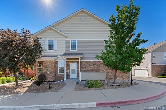 12784 Jasmine St Unit E, Thornton, CO 80602 - traditional-style home with stone siding, driveway, and an attached garage