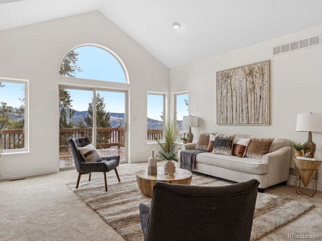 living area with high vaulted ceiling, visible vents, a mountain view, and light carpet