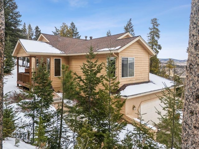 snow covered property featuring roof with shingles