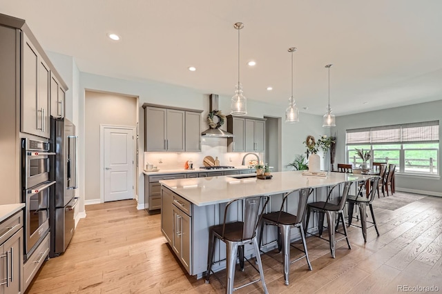 5668 Shadescale Way, Castle Rock, CO 80104 - kitchen featuring gray cabinetry, custom range hood, light wood-style flooring, a breakfast bar area, and stainless steel appliances