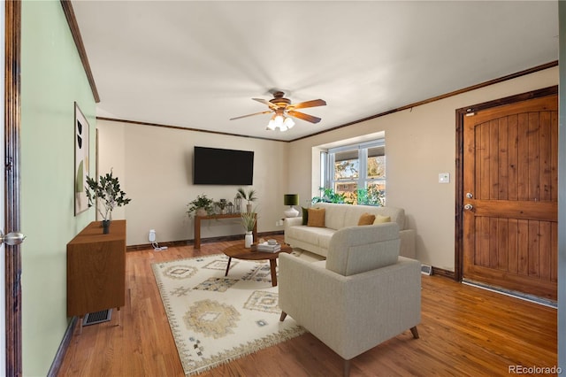 living room featuring ceiling fan, ornamental molding, and light wood-type flooring