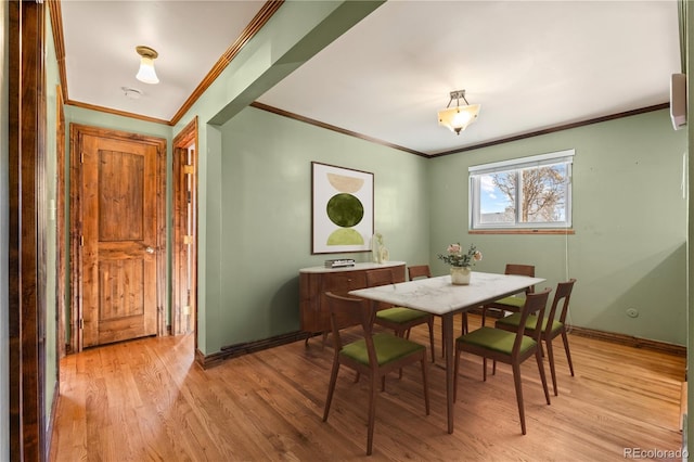 dining area with ornamental molding and light wood-type flooring