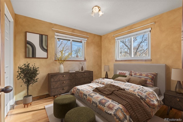 bedroom with a textured ceiling and light hardwood / wood-style flooring