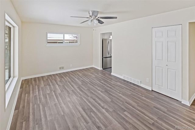 unfurnished bedroom featuring stainless steel fridge, light hardwood / wood-style floors, and ceiling fan