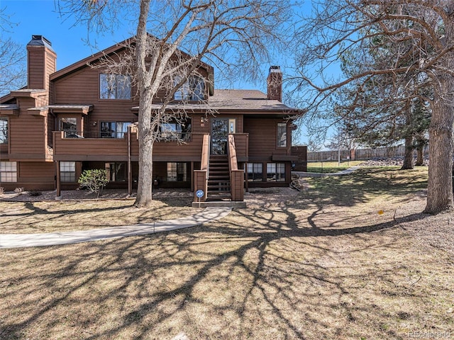back of house featuring a chimney, stairway, and fence