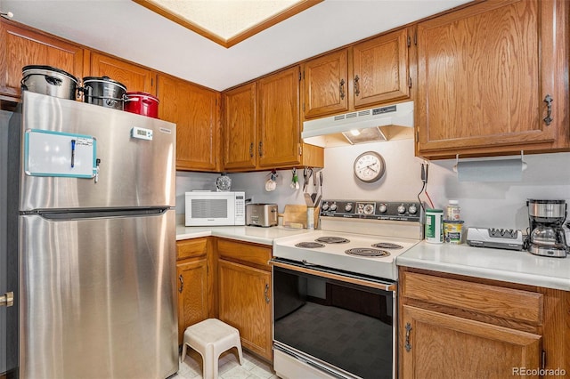 kitchen featuring brown cabinets, white appliances, light countertops, and under cabinet range hood
