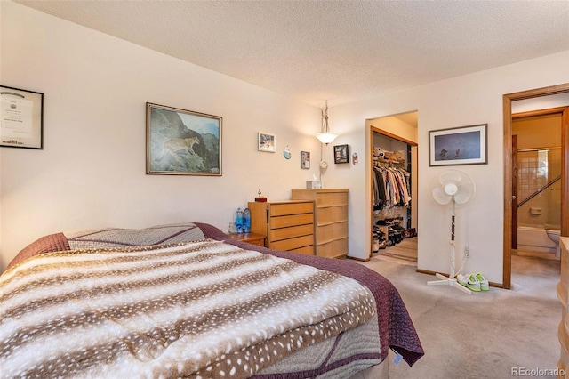 bedroom with ensuite bathroom, a closet, a textured ceiling, carpet, and a walk in closet