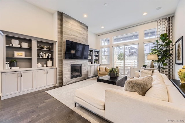 living room featuring dark wood-style floors, recessed lighting, a high ceiling, and a premium fireplace