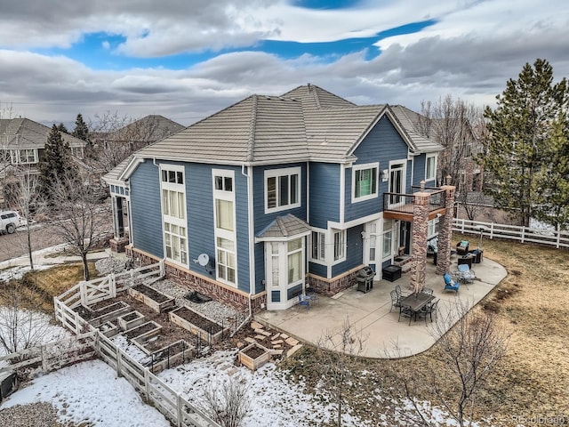 snow covered back of property featuring a balcony and a patio