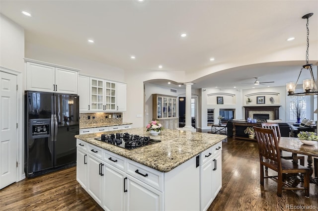 kitchen with black appliances, pendant lighting, white cabinets, a center island, and decorative columns