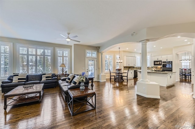 living room featuring ceiling fan, ornate columns, plenty of natural light, and dark hardwood / wood-style flooring