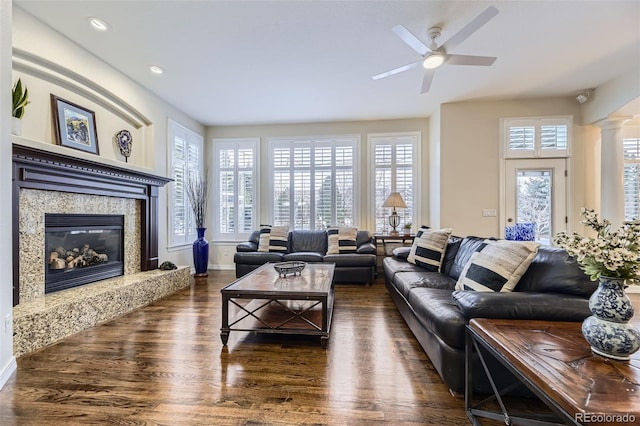 living room featuring a fireplace, ornate columns, ceiling fan, and dark hardwood / wood-style flooring