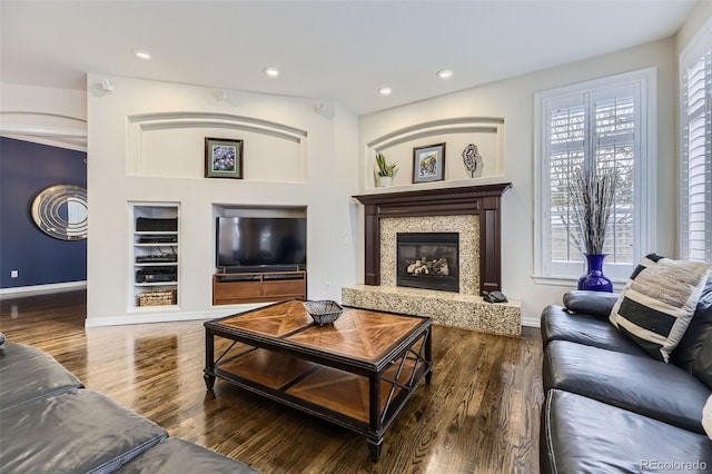 living room with built in features, hardwood / wood-style flooring, a high end fireplace, and plenty of natural light