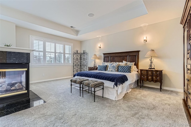 bedroom featuring a fireplace, carpet, and a tray ceiling