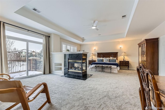 bedroom with access to outside, a tray ceiling, light carpet, and ceiling fan