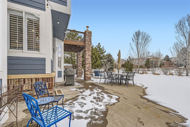 snow covered patio featuring a grill