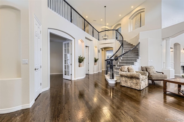 foyer featuring decorative columns, a towering ceiling, and hardwood / wood-style floors