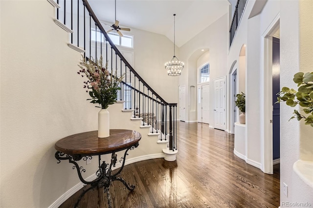 entrance foyer featuring high vaulted ceiling, dark wood-type flooring, and a notable chandelier