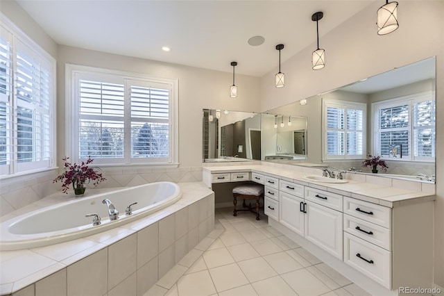 bathroom with tile patterned flooring, tiled tub, and vanity