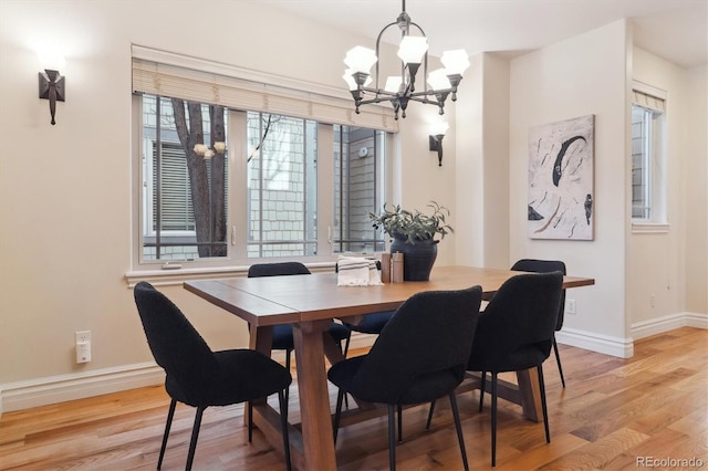 dining area with a notable chandelier, a wealth of natural light, and light hardwood / wood-style floors