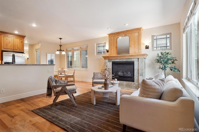 living room featuring a high end fireplace, a notable chandelier, and hardwood / wood-style floors