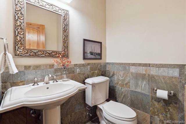 bathroom with toilet and tile walls