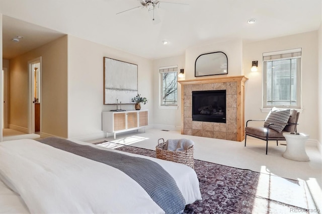 bedroom featuring ceiling fan, carpet flooring, a fireplace, and multiple windows