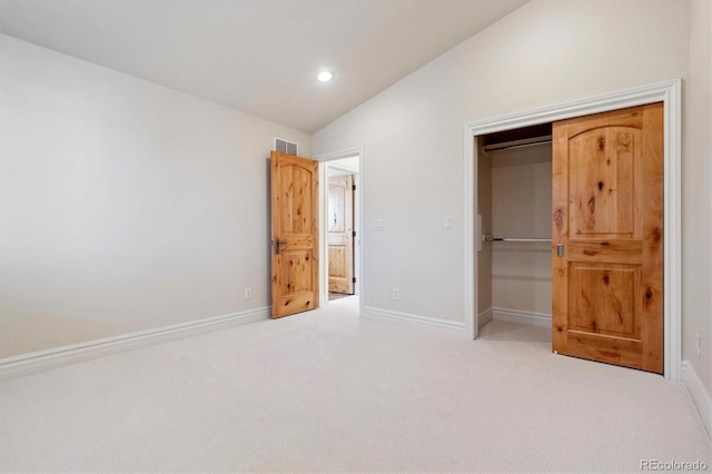 unfurnished bedroom featuring lofted ceiling, a closet, and carpet