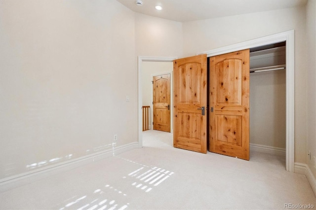 unfurnished bedroom with light colored carpet and a closet