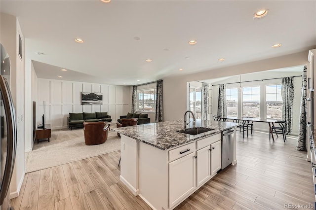 kitchen featuring white cabinetry, sink, dark stone counters, a kitchen island with sink, and stainless steel appliances