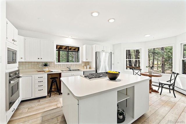 133 Mine Ln, Boulder, CO 80302 - kitchen with stainless steel appliances, light wood-style floors, backsplash, light countertops, and a center island